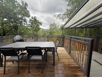 a table and chairs on a deck with a view at Balquhidder Braes Holiday Park Lodges, mostly with Hot Tubs and pet friendly, EV facilities in Lochearnhead