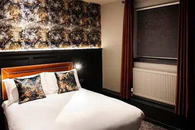 a bedroom with a white bed and a large window at The Coachman Hotel in Kilsyth
