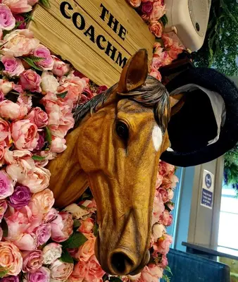 a statue of a horse on a wall with flowers at The Coachman Hotel in Kilsyth