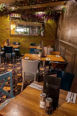 a dining room with wooden tables and chairs at The Coachman Hotel in Kilsyth