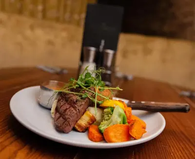a plate of food with meat and vegetables on a table at The Coachman Hotel in Kilsyth