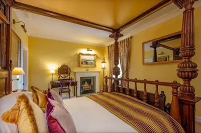 a bedroom with a bed and a mirror and a fireplace at Barcaldine Castle in Oban