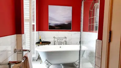 a bath tub in a bathroom with red walls at Dungallan Country House in Oban