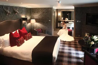 a bride is sitting on a bed in a hotel room at Eglinton Arms Hotel, BW Premier Collection in East Kilbride
