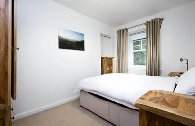 a white bedroom with a bed and a window at Trinity Lodge - Home with Private Garden and Parking in Edinburgh