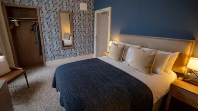 a bedroom with a large bed with a blue wall at Brisbane House Hotel in Largs