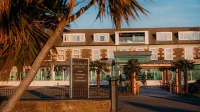 a building with palm trees in front of it at Brisbane House Hotel in Largs