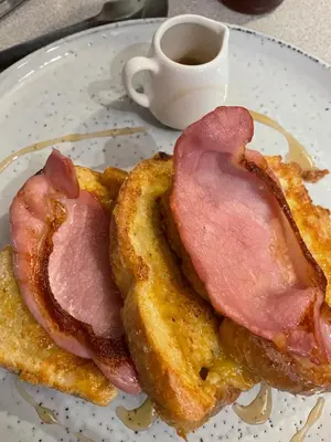 two pieces of bacon on a plate with a cup of coffee at Gowanlea Guest House in Balloch