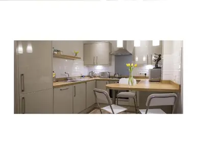 a kitchen with white cabinets and a table with chairs at The Lane Apartment in Edinburgh