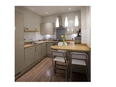a kitchen with white cabinets and a wooden table with stools at The Lane Apartment in Edinburgh