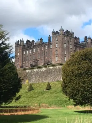 a large castle on top of a grassy hill at Lovely house next to Euchan River in Sanquhar