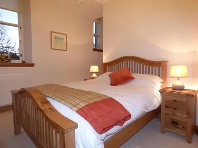 a bedroom with a wooden bed and a night stand with two lamps at The Pipers No 7 Lomond Castle in Balloch