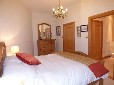 a bedroom with a white bed with a red pillow at The Pipers No 7 Lomond Castle in Balloch