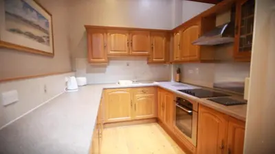 a kitchen with wooden cabinets and a stove at Stables Lodge in Balloch