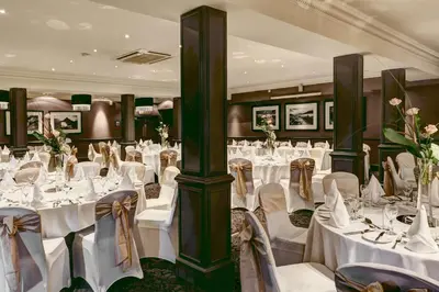 a banquet hall with white tables and chairs and flowers at Best Western Garfield House Hotel in Chryston