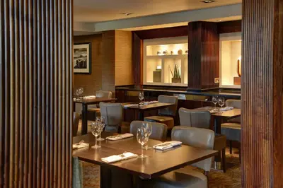 a restaurant with wooden tables and chairs with wine glasses at Best Western Garfield House Hotel in Chryston