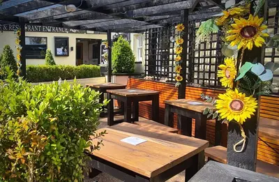 a patio with wooden tables and sunflowers on it at Black Bull Inn, Moffat in Moffat