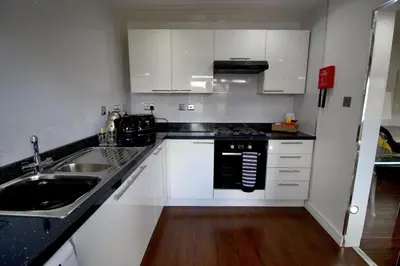 a kitchen with white cabinets and a black counter top at The Marlfield in Bellshill