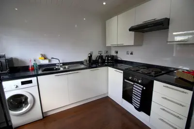 a kitchen with white cabinets and a sink and a dishwasher at The Marlfield in Bellshill