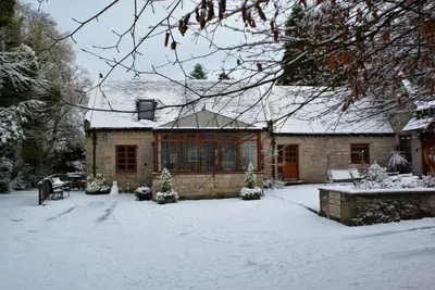 a house with snow on the ground in front of it at Smiddy Lodge in Balloch