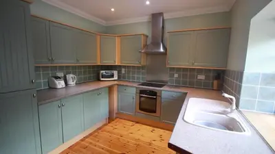 a kitchen with blue cabinets and a sink at Smiddy Lodge in Balloch
