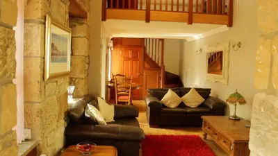 a living room with leather couches and a table at Smiddy Lodge in Balloch