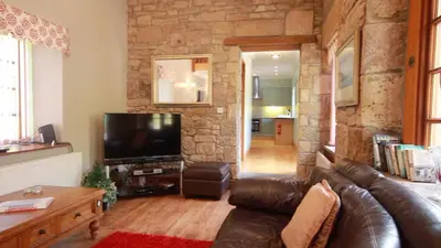 a living room with a leather couch and a television at Smiddy Lodge in Balloch