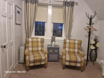 two chairs and a tv in a living room at St Leonards Guest House in Largs