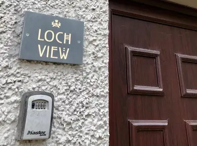 a sign on a building next to a wooden door at Hunters Lodge Apartments in Ballachulish