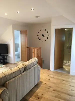 a living room with a couch and a clock on the wall at West Highland Way Rooms ED30002F in Milngavie
