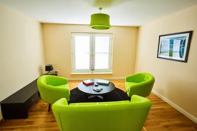 a living room with a table and two green chairs at Chapelhill in Helensburgh
