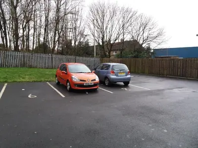 two cars parked in a parking lot next to a fence at Newtown Apartments in Boʼness
