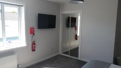 a bathroom with a shower with a mirror and a television at Newtown Apartments in Boʼness