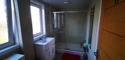 a bathroom with a shower and a sink and a mirror at Newtown Apartments in Boʼness