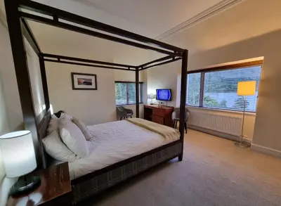 a bedroom with a canopy bed with a desk and a window at The Four Seasons Hotel in Saint Fillans