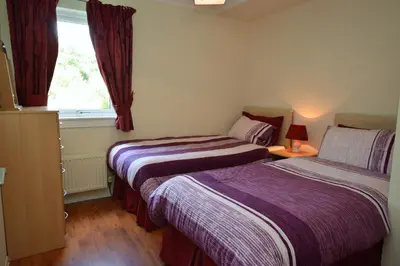 two beds in a small room with a window at Amber Lodge in Hunters Quay