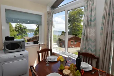 a kitchen with a table and a large window at Amber Lodge in Hunters Quay
