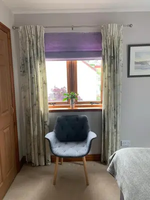 a bedroom with a chair in front of a window at Inverasdale in Oban