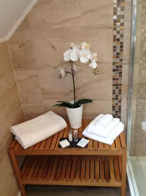 a bathroom with a table with two towels and a flower at Inverasdale in Oban