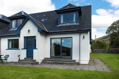 a white house with a blue door and windows at Stob Binnein Cottage in Crianlarich