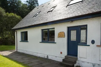 a white house with blue windows and a blue door at Stob Binnein Cottage in Crianlarich