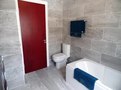a bathroom with a toilet and a tub and a red door at Signature - Langlands House in Glasgow