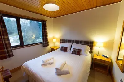 a bedroom with a large bed with two chairs on it at Eagle Lodge with stunning loch and mountain view in Crianlarich