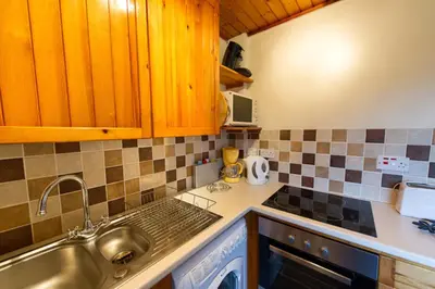 a kitchen with wooden cabinets and a sink at Eagle Lodge with stunning loch and mountain view in Crianlarich