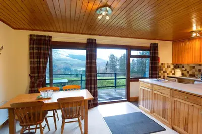 a kitchen with a table and chairs and a large window at Eagle Lodge with stunning loch and mountain view in Crianlarich