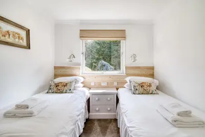 two twin beds in a room with a window at Gamekeeper Lodge loch and mountain view free wifi in Crianlarich