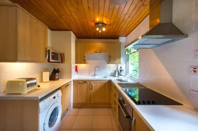 a kitchen with wooden cabinets and a washer and dryer at Kestrel Lodge with mountain view free wifi in Crianlarich