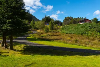 a winding road through a field with trees and houses at Kestrel Lodge with mountain view free wifi in Crianlarich