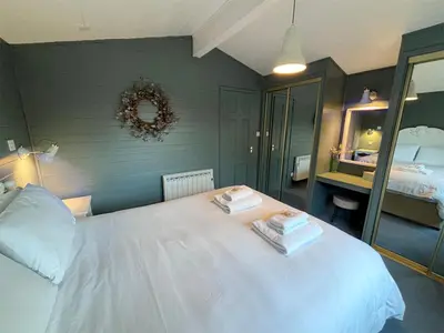 a bedroom with a white bed with two towels on it at Lapwing Lodge with loch and mountain view in Crianlarich