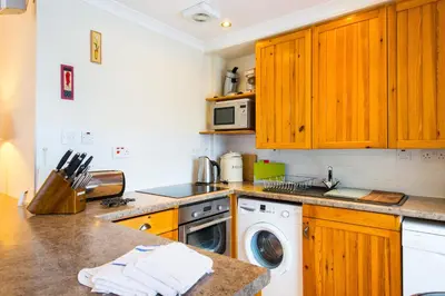 a kitchen with wooden cabinets and a washer and dryer at Osprey Lodge with river and mountain view in Crianlarich